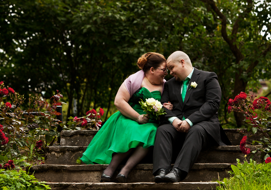 A bride in green wedding dress sharing a joyful moment with the groom wearing black suit with green tie matching the bride's dress.